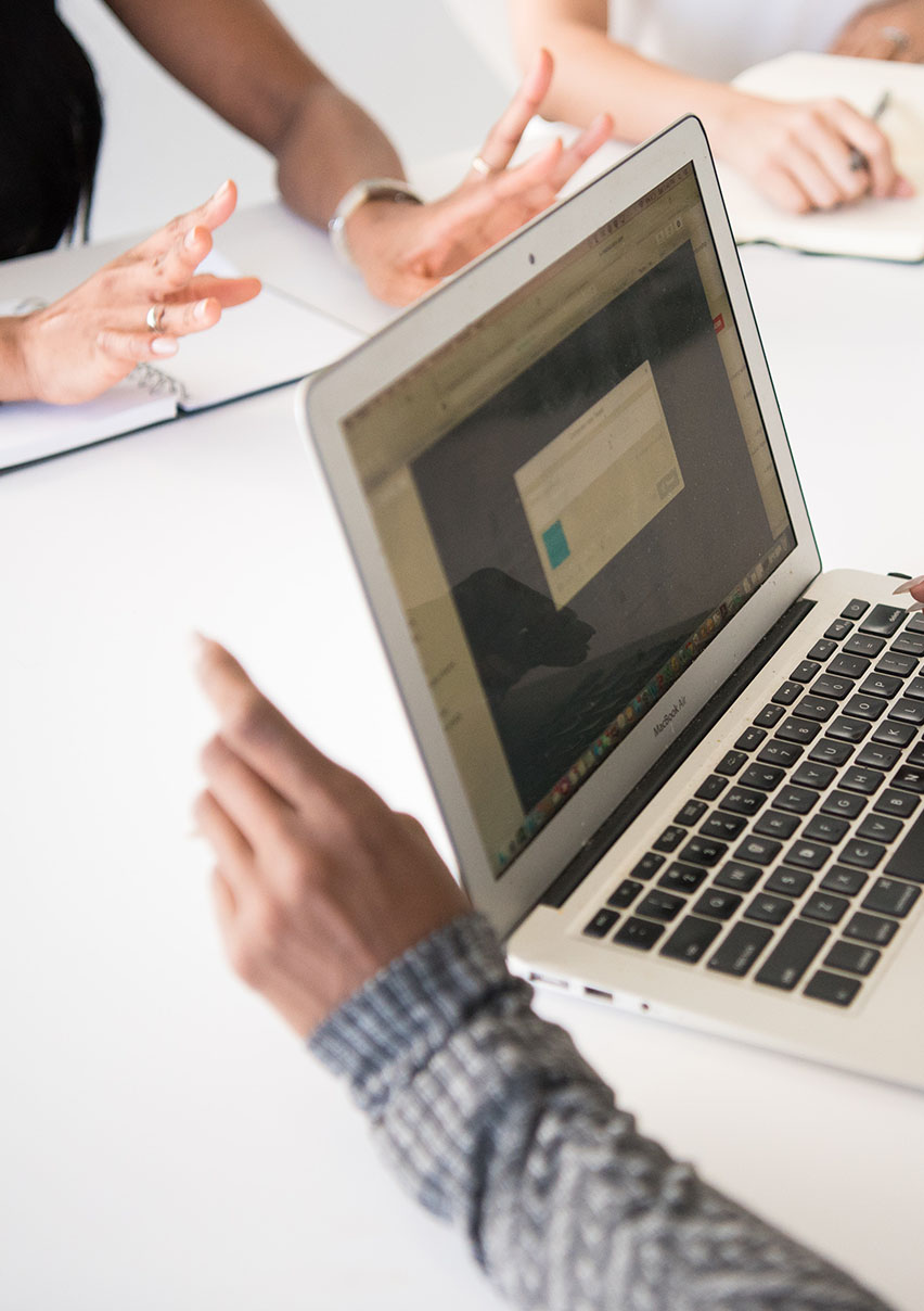Ausschnitt einer Meeting-Situation mit Laptop an einem modernen Arbeitsplatz
