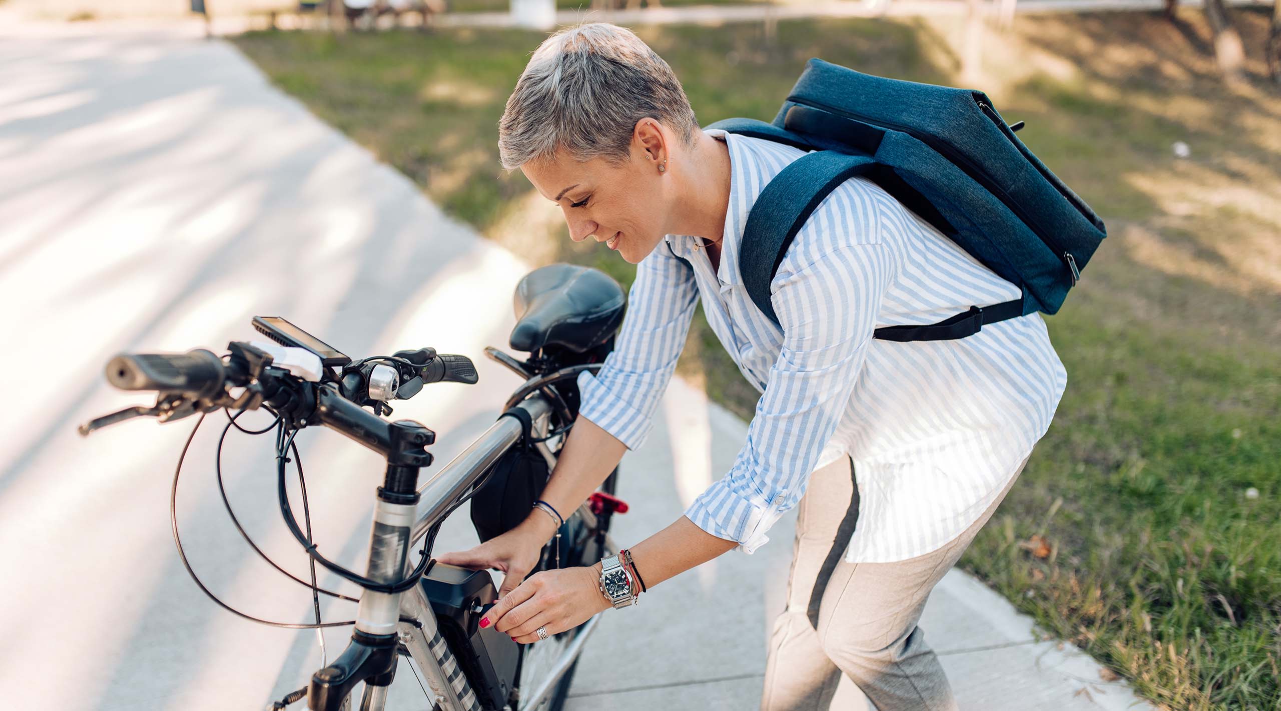 Frau mit E-Bike beim Installieren der Batterie